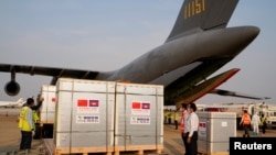 Workers stand next to the shipment of 600,000 doses of the coronavirus disease (COVID-19) vaccines donated by China at the Phnom Penh International Airport, in Phnom Penh, Cambodia February 7, 2021. (REUTERS/Cindy Liu)