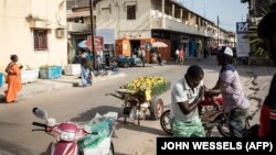 Un vendeur d'oranges plaisante avec un ami devant un vieux bâtiment colonial du centre de Ziguinchor le 11 février 2021.