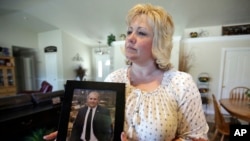 ARCHIVO - En esta fotografía del 13 de julio de 2016, Laurie Holt sostiene una fotografía de su hijo Joshua en su casa en Riverton, Utah. Laurie Holt, que pasó casi dos años presionando para que su hijo fuera liberado de una cárcel venezolana, murió a los 50 años.