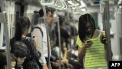 Penumpang kereta bawah tanah di Singapura asyik dengan ponsel pintar mereka (30/4). (AFP / Roslan Rahman)