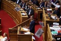 Protesters throw fliers as Greece's Prime Minister Kyriakos Mitsotakis speaks on the final day of a censure motion debate against the conservative government in Parliament over a deadly rail disaster, in Athens, Greece, March 7, 2025.