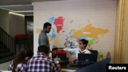 Sachin, 19, offers sweets to the receptionist at Western Overseas, an institute providing coaching for English language proficiency tests and visa consultancy, after his visa was approved, in Ambala, India, August 4, 2022. REUTERS/Anushree Fadnavis