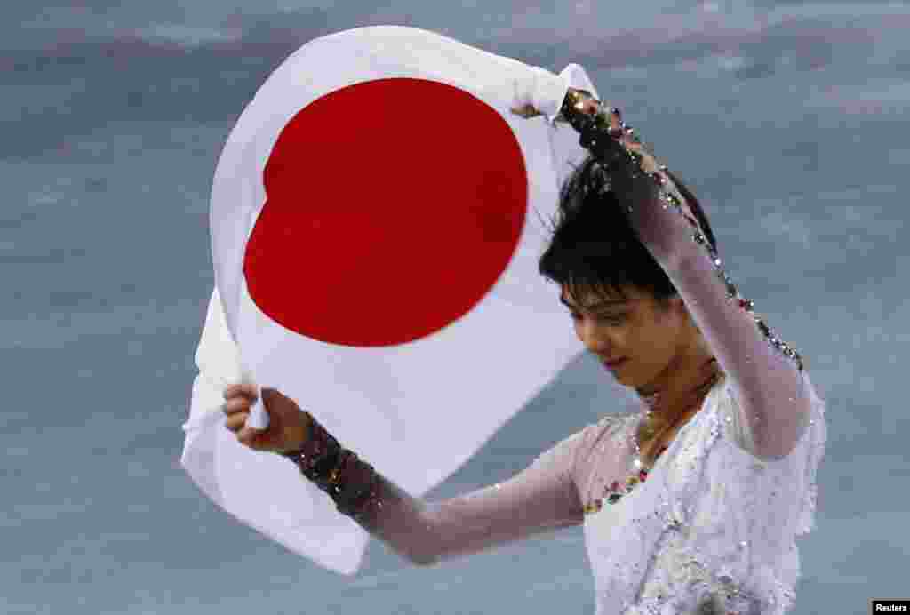 Japan&#39;s Yuzuru Hanyu carries the Japanese flag after winning gold in the men&#39;s free skating event at the 2014 Winter Olympics, February 14, 2014.&nbsp;