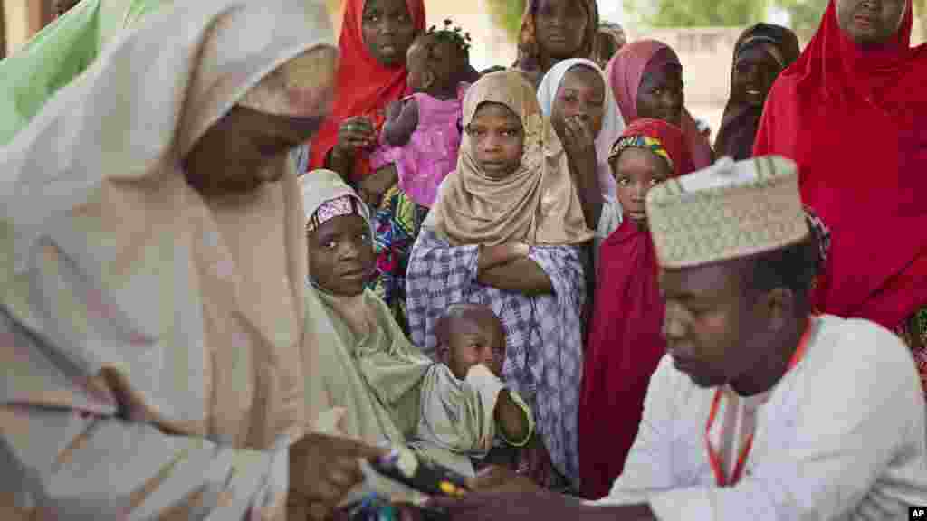 De jeunes filles nigérianes de la tribu des Hausa attendent leurs mères qui font la queue pour valider leurs cartes de vote, à un bureau de vote dans une école islamique de Daura, le nord du Nigeria, samedi 28 mars 2015.