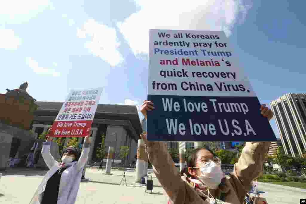한국 서울 주한 미국 대사관 앞에서 도널드 트럼프 미국 대통령 지지자들이 트럼프 대통령과 멜라니아 트럼프 여사의 신종 코로나바이러스 감염 회복을 기원하는 문구를 들고 있다. 
