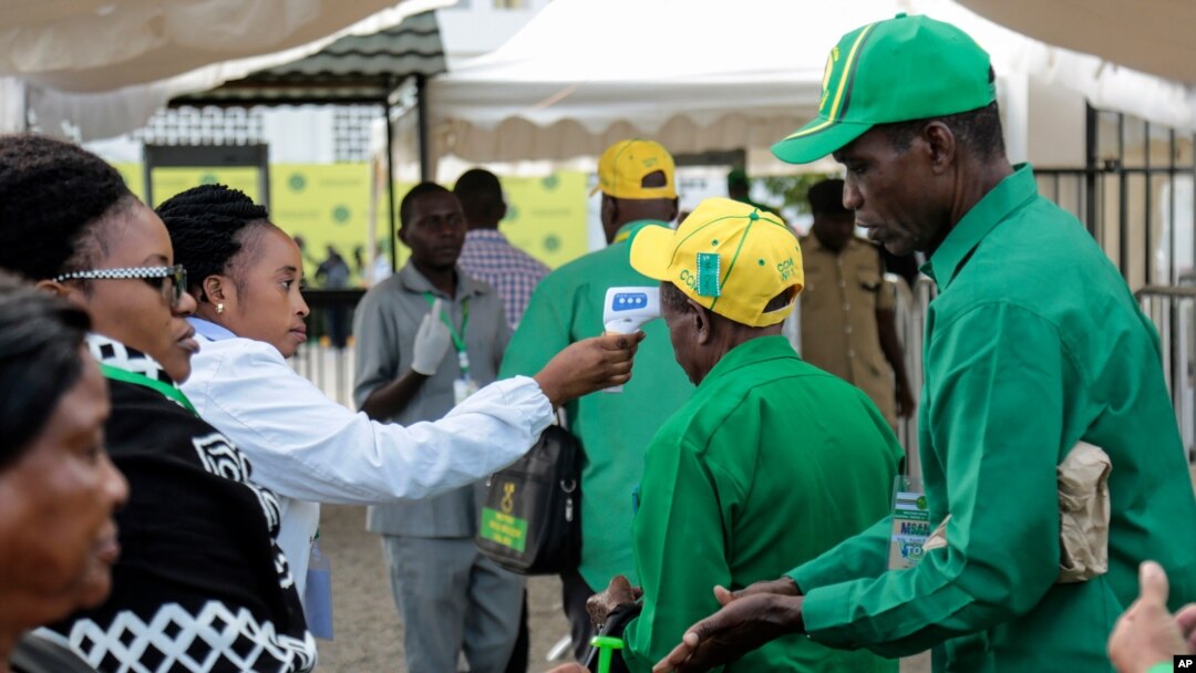 FILE - Party members have their temperature checked and sanitize their hands as a precaution against the coronavirus at the national congress of the ruling Chama cha Mapinduzi (CCM) party in Dodoma, Tanzania, July 11, 2020.