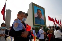 FILE - Tourists stand near a portrait of Sun Yat-sen, regarded as the founding father of modern China, in Beijing, Oct. 1, 2020. Negative perceptions of China have risen in many of the world's advanced economies, the Pew Research Center found.