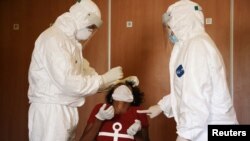 FILE - Health workers test a migrant domestic worker from Africa for the coronavirus disease at a hotel, before she travels back to her country, in Beirut suburbs, Lebanon, Oct. 5, 2020. 