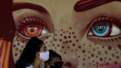 Women wear face masks amid the new coronavirus pandemic as they wait for a quick test at a COVID-19 testing site set up on a public school's basketball court in the Estrutural neighborhood of Brasilia, Brazil, Tuesday, May 26, 2020. According to…
