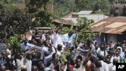 Leader of the opposition party Forum for Democratic Change Kizza Besigye, background center right, beside his wife Winnie Byayima, left, waves to large crowds of supporters as he returns from Nairobi after medical treatment.