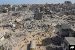 FILE - Palestinians walk through the destruction left by the Israeli air and ground offensive on the Gaza Strip near Shifa Hospital in Gaza City, on April 1, 2024.