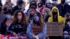 People hold signs of support at a memorial to remember the victims of the Atlanta area massage parlors shootings during a memorial in Kansas City, Mo., March 28, 2021. 