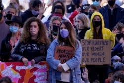 FILE - People hold signs of support at a memorial to remember the victims of the Atlanta area massage parlors shootings during a memorial in Kansas City, Mo., March 28, 2021.