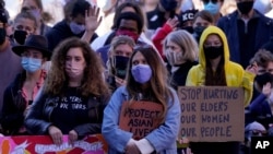 People hold signs of support at a memorial to remember the victims of the Atlanta area massage parlors shootings during a memorial in Kansas City, Mo., March 28, 2021. 