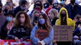 FILE - People hold signs of support at a memorial to remember the victims of the Atlanta area massage parlors shootings during a memorial in Kansas City, Mo., March 28, 2021.