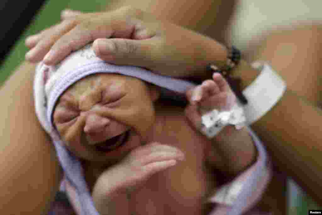 Sueli Maria (obscurci) porte sa fille Milena, qui a une microcéphalie, dans un hôpital de Recife, Brésil, 28 janvier 2016.