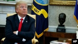 President Donald Trump listens during a meeting with North Korean defectors where he talked with reporters about allowing the release of a secret memo on the FBI's role in the Russia inquiry, in the Oval Office of the White House, Feb. 2, 2018, in Washington.