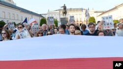 A giant Polish national flag is spread in front of anti-government protesters raising placards reading: Constitution. The protesters are gathered in front of the presidential palace in Warsaw, Poland, July 22, 2017.