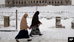 Afghan women walk past the palace of the late King Amanullah Khan, which was destroyed during the civil war in early 1990s, in Kabul, Afghanistan, Dec. 30, 2013.