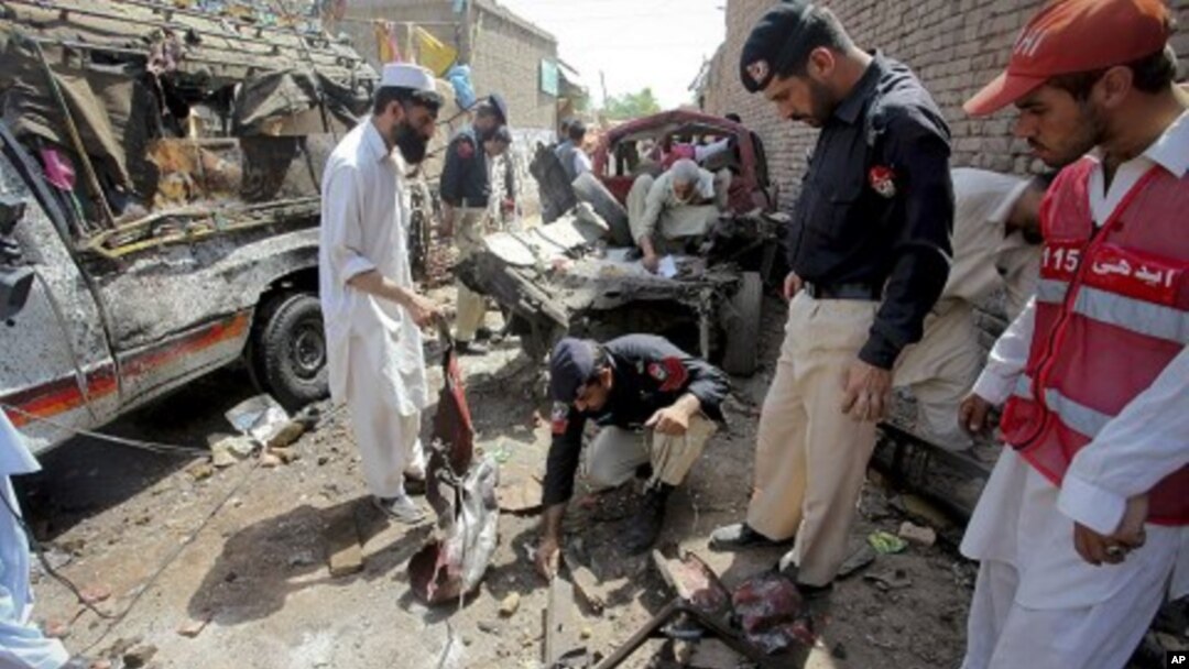 Pakistani police officers examine the site of a bomb blast in a bus stand in Matani near Peshawar, Pakistan, June 5, 2011