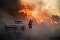 FILE - Firefighter Raymond Vasquez battles the Silverado Fire, in Irvine, Calif., Oct. 26, 2020.