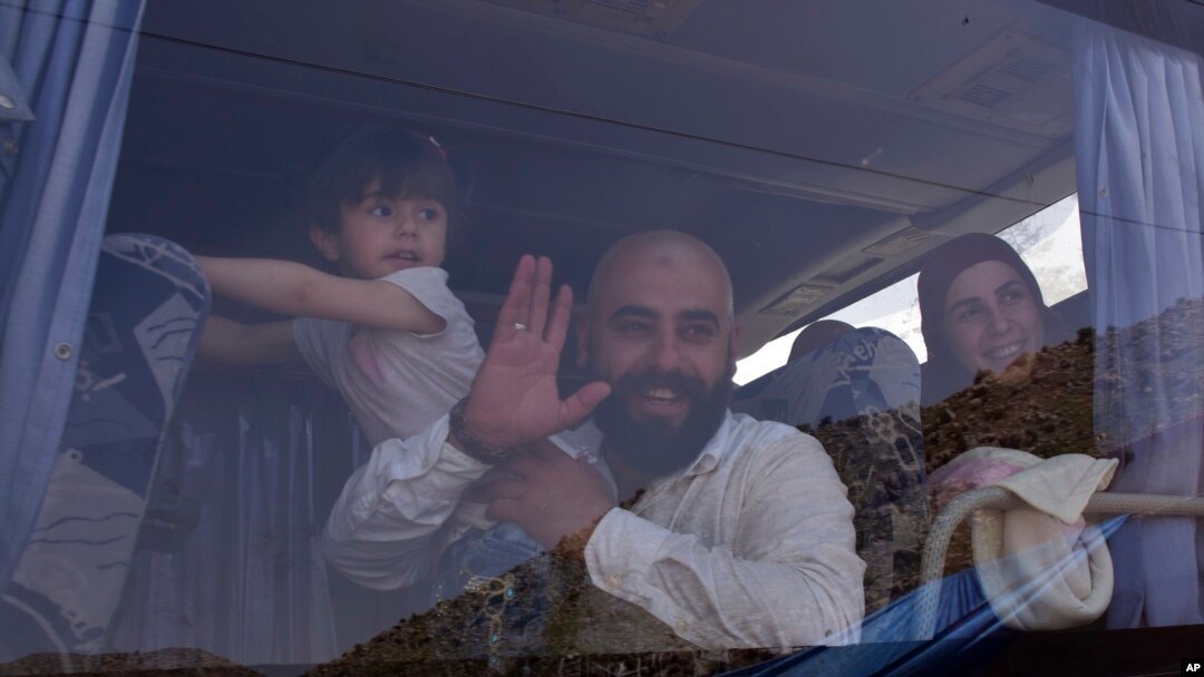 FILE - Displaced people who fled the Syrian war look through a bus window as they prepare to return to their village of Beit Jinn, near the Lebanese-Syrian border, in Shebaa, southern Lebanon, April, 18, 2018.