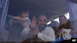 FILE - Displaced people who fled the Syrian war look through a bus window as they prepare to return to their village of Beit Jinn, near the Lebanese-Syrian border, in Shebaa, southern Lebanon, April, 18, 2018.