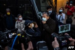 FILE - A police officer, center left, gestures at pro-democracy activist Lee Cheuk Yan while he chants slogans after media tycoon Jimmy Lai left in a prison van from the Court of Final Appeal in Hong Kong, Dec. 31, 2020.
