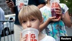 Benjamin, 8, minum soda berukuran besar saat ikut serta dengan ayahnya dalam protes terhadap larangan penjualan soda berukuran besar di New York. (Foto: Dok)