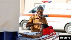 A man stands next to an injured Palestinian, who will receive treatment in an Egyptian hospital, at the Rafah border crossing, November 1, 2023. 