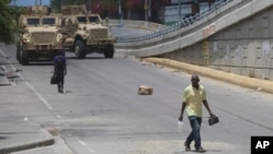 Un hombre camina frente a dos vehículos blindados de los policías kenianos que integran una fuerza multinacional respaldada por la ONU, en Puerto Príncipe, Haití, el miércoles 4 de septiembre de 2024.