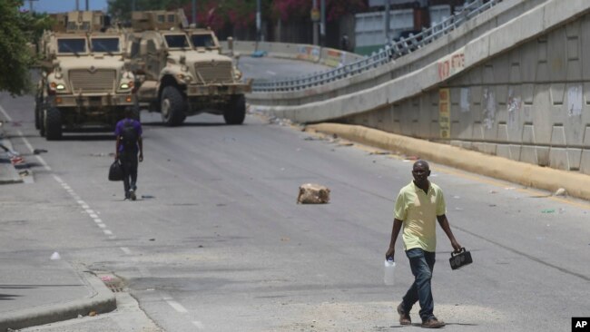 Un hombre camina frente a dos vehículos blindados de los policías kenianos que integran una fuerza multinacional respaldada por la ONU, en Puerto Príncipe, Haití, el miércoles 4 de septiembre de 2024.