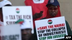 A protestor holds a placard during a protest in Abuja on February 27, 2024.