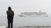 A man stands on the shores of the Bering Sea to watch the luxury cruise ship Crystal Serenity, anchored just outside Nome, Alaska, because it was too big to dock at the Port of Nome, Aug. 21, 2016.