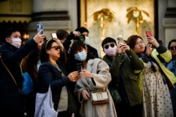 People, some wearing protective masks amid a coronavirus outbreak, take photos in central Milan, Italy, Feb. 24, 2020.