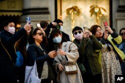 People, some wearing protective masks amid a coronavirus outbreak, take photos in central Milan, Italy, Feb. 24, 2020.
