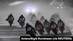 Pembalap mengendarai sepeda motor di tengah hujan lebat menjelang Race 2 Kejuaraan Dunia Superbike di Sirkuit Jalan Internasional Mandalika di Lombok, Nusa Tenggara Barat, 21 November 2021. (Foto: Antara/Sigid Kurniawan via REUTERS)