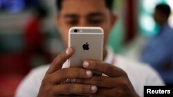 FILE - A salesman checks a customer's iPhone at a mobile phone store in New Delhi, India.