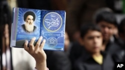 An Iraqi man holds a picture of top Shiite cleric Grand Ayatollah Ali Husseini al-Sistani at a campaign rally for Ammar al-Hakim in Baghdad 5 Mar 2010