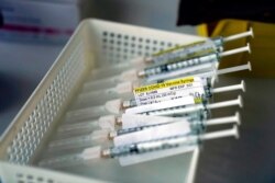 FILE - Syringes containing the Pfizer-BioNTech COVID-19 vaccine sit in a tray in a vaccination room at St. Joseph Hospital in Orange, Calif., Jan. 7, 2021.