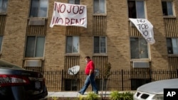 FILE - In this May 20, 2020 file photo, signs that read "No Job No Rent" hang from the windows of an apartment building in Northwest Washington. 