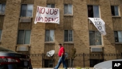 FILE - In this May 20, 2020 photo, signs that read "No Job No Rent" hang from the windows of an apartment building in northwest Washington. 