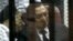 FILE - Ousted Egyptian President Hosni Mubarak, sits in the defendants cage behind protective glass, during a court hearing as he listens to his son Gamal, left, in Cairo, Egypt, May 2014.