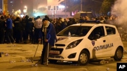 A man rests by a police car during clashes between protesters and the police in front of the parliament building in Skopje, Macedonia, April 27, 2017. Demonstrators stormed parliament Thursday and attacked lawmakers to protest the election of a new speaker despite a months-old deadlock in efforts to form a new government.