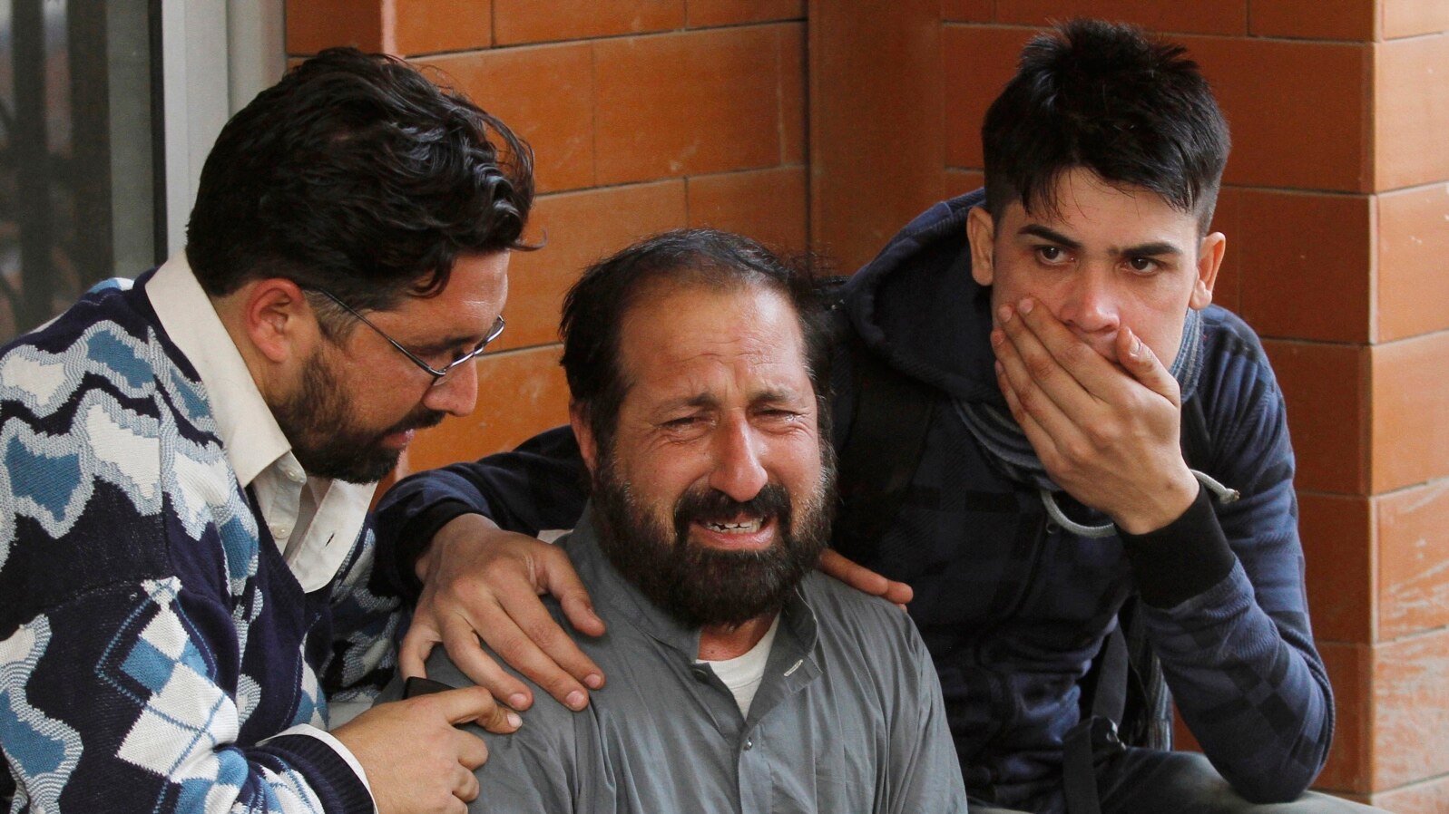 FILE - Relatives of a student who was injured during an attack by Taliban gunmen on the Army Public School comfort each other outside Lady Reading Hospital in Peshawar, Dec. 16, 2014.