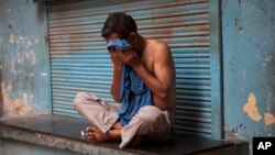 FILE - An Indian man wipes sweat off his face on a hot summer day in New Delhi, India, May 24, 2015. 