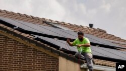 FILE: Workers install solar planers on the roof of a house in Rivas Vaciamadrid, Spain, Thursday, Sept. 15, 2022. The energy crisis is accelerating the installation of solar panels by residential communities in Spain who want to become self-sufficient. 