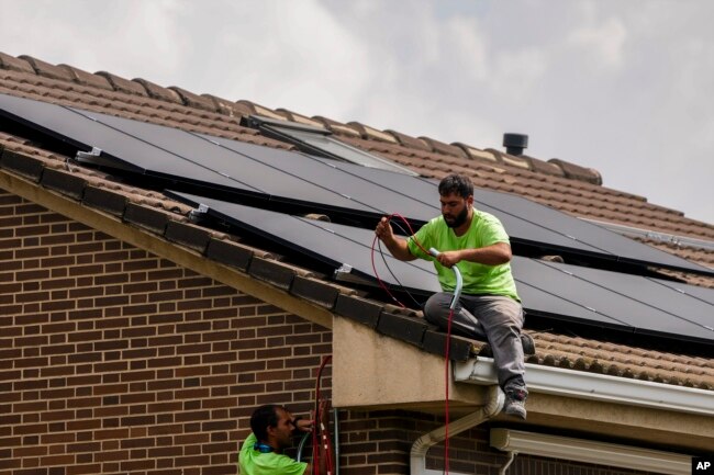 FILE - Workers install solar planers on the roof of a house in Rivas Vaciamadrid, Spain, Thursday, Sept. 15, 2022. (AP Photo/Manu Fernandez)