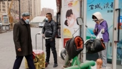 Sejumlah warga mengenakan masker berjalan di Aksu, di Wilayah Xinjiang, China, 18 Maret 2021. (Foto: Ng Han Guan/AP Photo)
