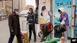 Sejumlah warga mengenakan masker berjalan di Aksu, di Wilayah Xinjiang, China, 18 Maret 2021. (Foto: Ng Han Guan/AP Photo)
